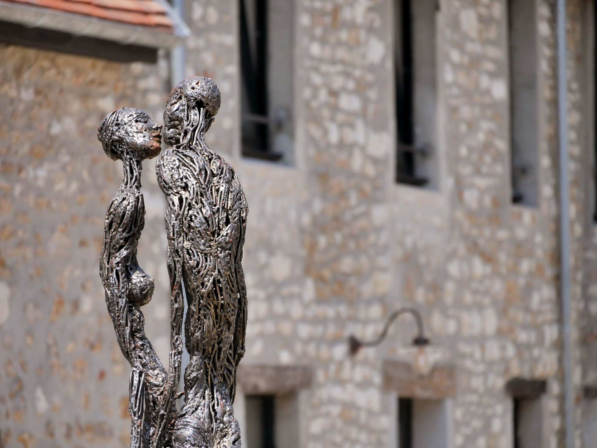 Sculpture contemporaine représentant deux figures humaines abstraites face à face, devant la façade de la maison d'hôtes Val Trebbia